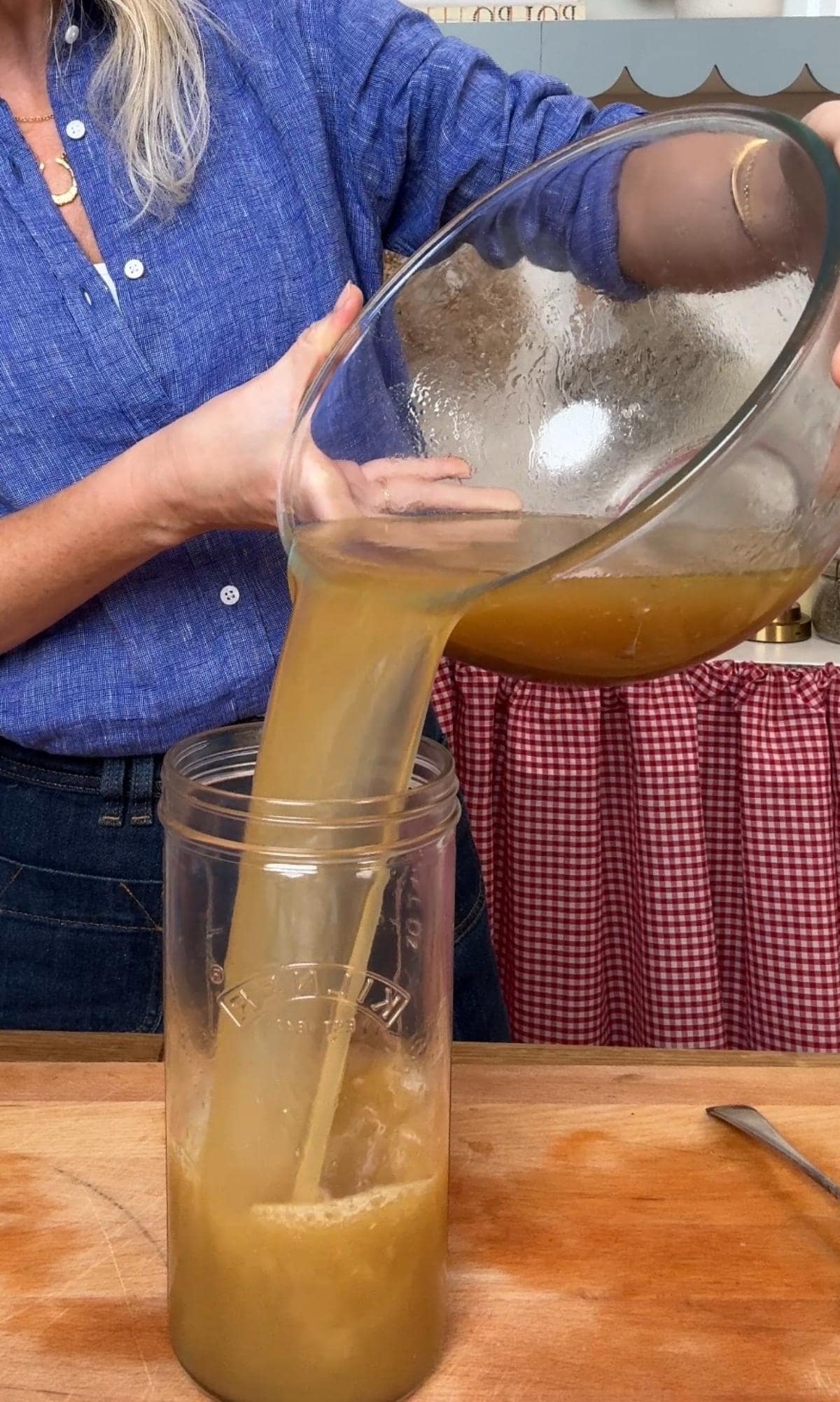 pouring chicken stock in a jar.